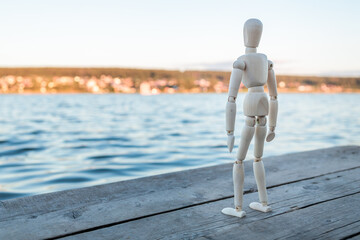 The wooden figure resembles a man standing against the background of a lake
