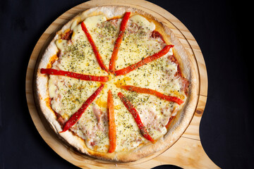 pizza de queso y morrones en tabla de madera y fondo negro