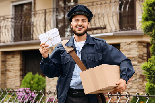 Handsome postman with parcel and letters on street