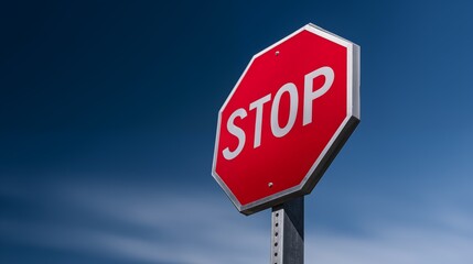 Obraz premium Red stop sign against clear blue sky, road signage close up, traffic safety concept