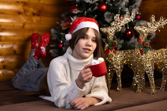  girl is enjoying a hot drink in a festive setting with Christmas decorations.