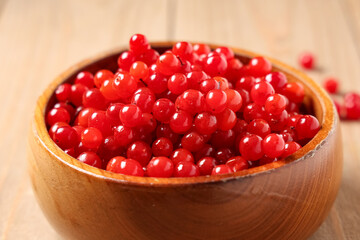 Bowl with fresh viburnum berries on wooden background, closeup