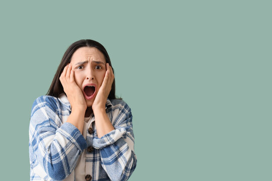 Young woman screaming on green background