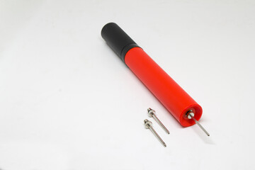 Angled close-up of a red-and-black handheld ball pump, isolated on white