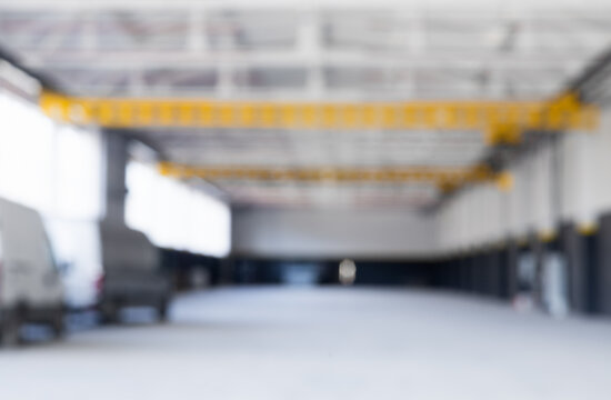 Defocus blurred background empty industrial workshop with an overhead crane. A bright yellow crane is suspended from the ceiling. The interior features clean white black walls