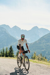Cyclist riding on a scenic mountain road.  Athlete enjoys outdoor activity, exercising and adventure travel with bike in the Alps. Beautiful mountain landscape view on background.
