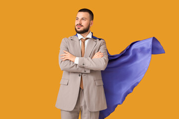Young businessman with superhero cape on orange background © Pixel-Shot
