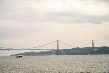 Ferry boat on Tagus River with 25 de Abril Bridge and Christ the King monument Lisbon Portugal
