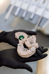 Orthodontic palatal expander models in gloved hands at dental clinic, closeup