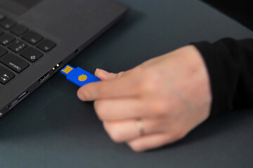 Female IT security technician in a tech office connects blue USB drive to a laptop