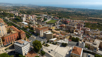 Aerial view of the municipal stadium in Agrigento, Sicily, Italy. It is a small football stadium located on the outskirts of city. In background, the Sicilian coast overlooking the Mediterranean sea.