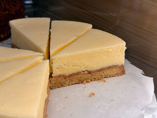 Cheesecake slices on parchment in bakery display. Dessert photography, pastry craftsmanship, and culinary aesthetics of homemade sweetness.