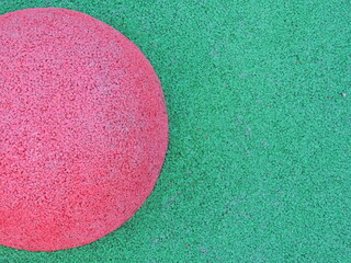Pink circle on a green background as a geometric colorful abstraction, fragment of playground covering with colorful elements and abstract structure, rubber crumb material in sports flooring