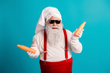 Cheerful santa look with towel turban and red suspenders holding orange bottles in a bright blue studio for festive humor and holiday style