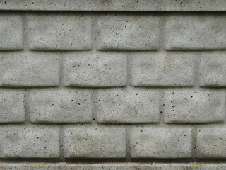 Close-up of a gray concrete wall with foam block texture as a background rough monochromatic convex abstraction, a fragment of a fence or building facade made of blocks as a textured empty backdrop