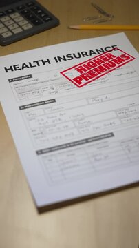 Vertical health insurance form stamped &ldquo;HIGHER PREMIUMS&rdquo; in red, symbolizing rising costs after the end of ACA subsidy credits in 2025. Fictional data on form. 14938  	