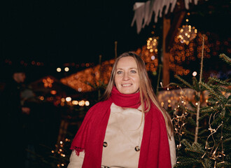 Festive young caucasian female enjoying christmas market at night