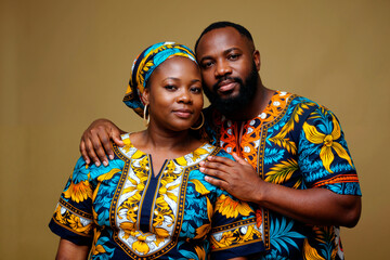 Obraz premium Portrait of young adult Black woman and young adult Black man standing close together looking into camera man resting hand on woman's shoulder both wearing patterned clothing