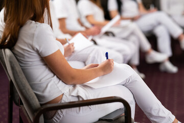 Close up of a student holding a pen and writing notes in a notebook during a professional training and education session in a wellness and therapy course