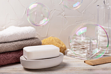 Health and hygiene. White soap bar placed on ceramic dish, surrounded neatly stacked towels and floating bubbles, creating calming atmosphere in modern bathroom, emphasizing cleanliness and relaxation
