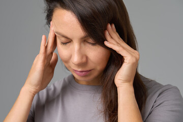 Close-up portrait of woman pressing temples with eyes closed, concept of stress