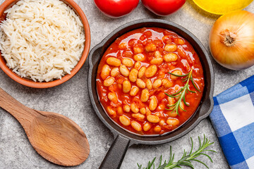 Baked bean dish in cast iron pan on vintage background.