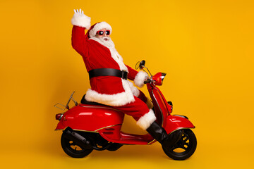Santa on a bright red scooter waves hello as he rides against a bold yellow background for a festive Christmas moment perfect for holiday © deagreez