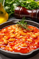 Baked bean dish in cast iron pan on black background. 