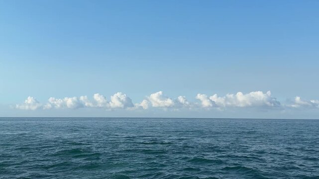 Ocean blue waves, sky and low clouds.