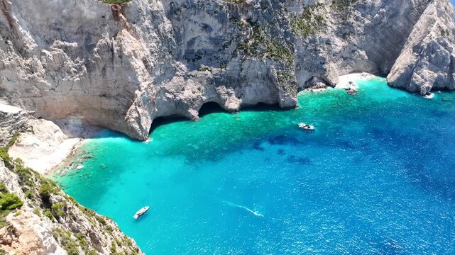 Aerial drone video of famous steep white rocky cliffs creating beautiful coves and turquiose sea caves of Kampi visited by small boats and yachts in northern part of Zakinthos island, Ionian, Greece