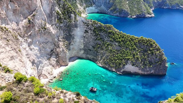 Aerial drone video of famous steep white rocky cliffs creating beautiful coves and turquiose sea caves of Kampi visited by small boats and yachts in northern part of Zakinthos island, Ionian, Greece