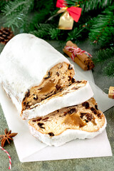 Whole sliced Christmas marzipan stollen with powdered sugar,surrounded by decorations fir branches
