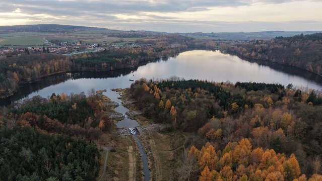 Aerial view of a lake surrounded by autumn foliage and a small village. Perfect for travel brochures nature backgrounds website design and advertising - Powered by Adobe
