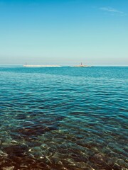 Obraz premium Clear Blue Sea with Shallow Water and Red Lighthouse