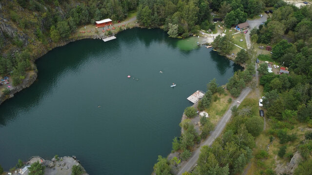 Aerial view of a clear lake with people swimming. Ideal for travel brochures showcasing recreational activities