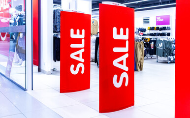 Sale signs stand at the entrance to a clothing boutique with sale information. Promotion, advertising, shopping and black friday concept