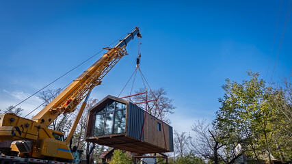 The process of transporting a house with a truck crane.