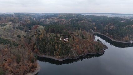 Scenic aerial view of a modern house nestled among vibrant autumn foliage overlooking a calm lake. Perfect for travel brochures real estate advertising or nature backgroun © rikajiMiAda