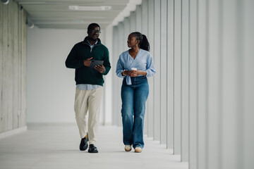 Business colleagues walking and conversing in modern office corridor