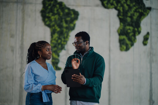 Business colleagues discussing strategy using tablet against green world map