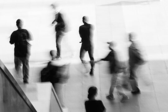 Abstract black and white motion blur of people walking in an urban environment, representing modern life, movement, and connection.
