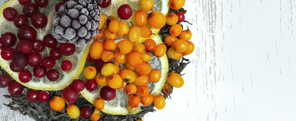 Delicious tea with raspberries,berries, and leaves on a wooden table.Place for text,natural tea in a cup with fresh berries and mint,red berry tea,naturopathy,medicinal syrup,or tincture.Medicinal