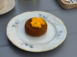 Elegant dessert with honeycomb decoration served on porcelain plate. Sweet treat, patisserie style, and gourmet presentation in outdoor cafe.