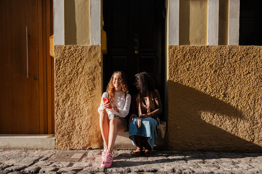 Two women friends smiling using smartphone on holiday - Powered by Adobe