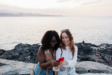 Diverse women friends enjoying Canary Islands holidays with smartphone
