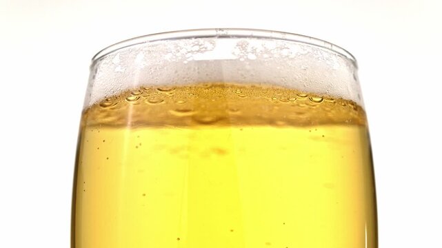 A glass of beer is filled with bubbles and foam. The glass is half full, and the foam is rising to the top. Concept of relaxation and enjoyment, as the bubbles and foam suggest that the beer is fresh