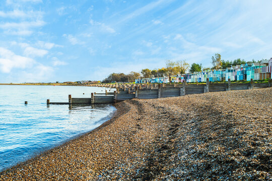 The pebble beach, wooden groyne water breakers, and quaint painted beach huts of Tankerton, Whitstable in Kent, UK.