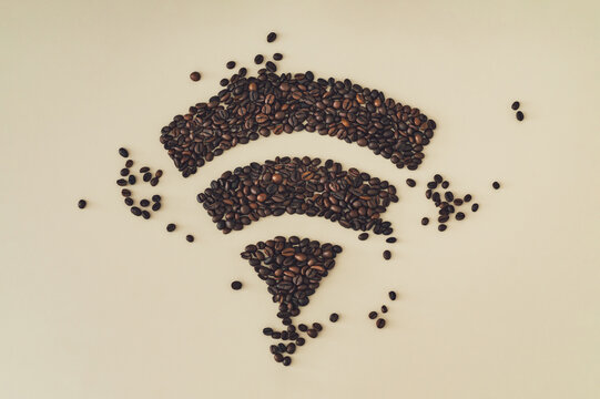 Coffee beans shaped like Wi-Fi symbol on beige background. Coffee network concept for cafe or barista theme. Perfect for coffee shops, cafe branding or lifestyle blogs. Coffee connection flat lay.