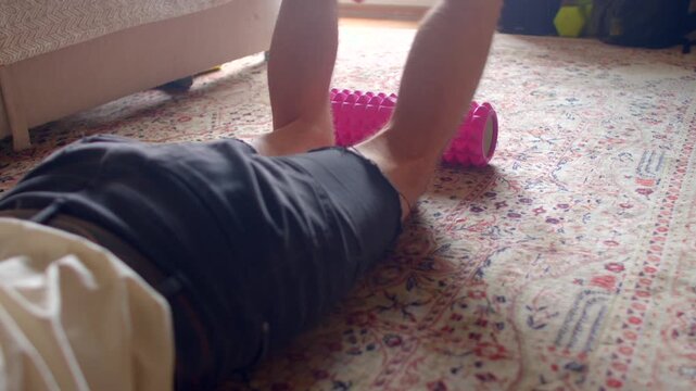 legs lying on carpet rolling pink foam roller under hamstrings gentle glide for tissue release slow controlled