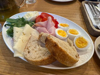 Morning plate with eggs, vegetables and bread on wooden table. Healthy diet, homemade breakfast, and natural nutrition balance.